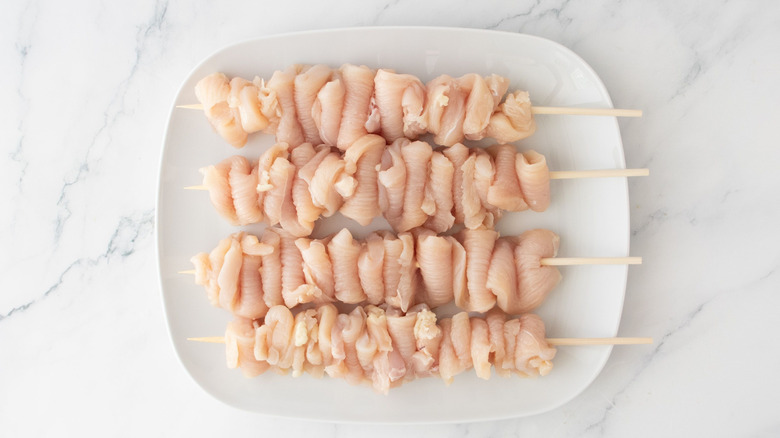 Raw chicken skewers on plate