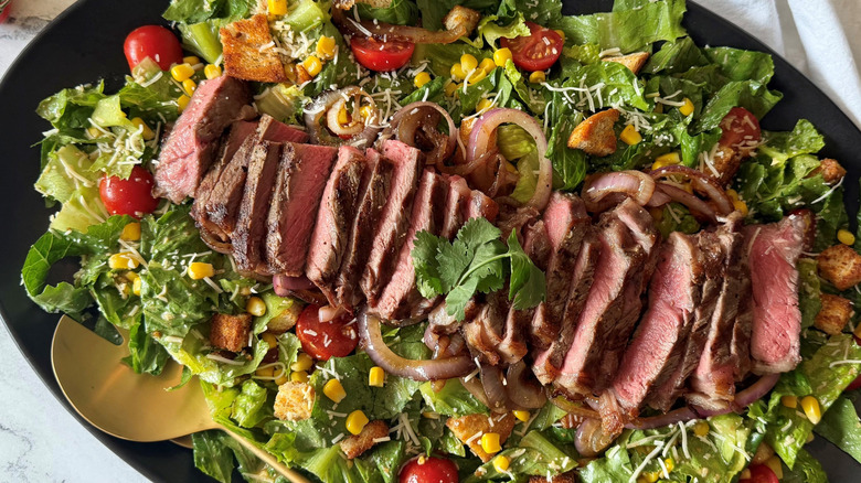 Cowboy Caesar salad in serving platter topped with sliced steak