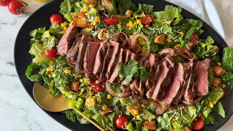 Cowboy Caesar salad topped with sliced steak