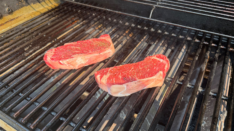 Raw steaks on grill