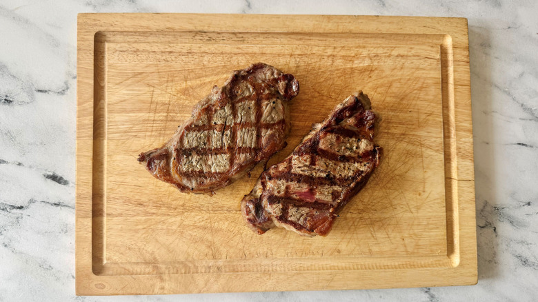 Grilled steaks on wooden board