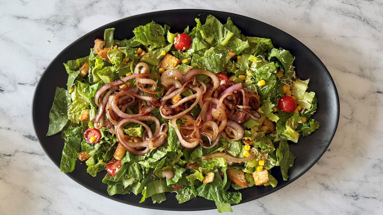 Cowboy Caesar salad on serving platter topped with onions