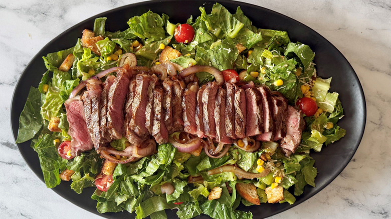 Cowboy Caesar salad on serving platter topped with sliced steak