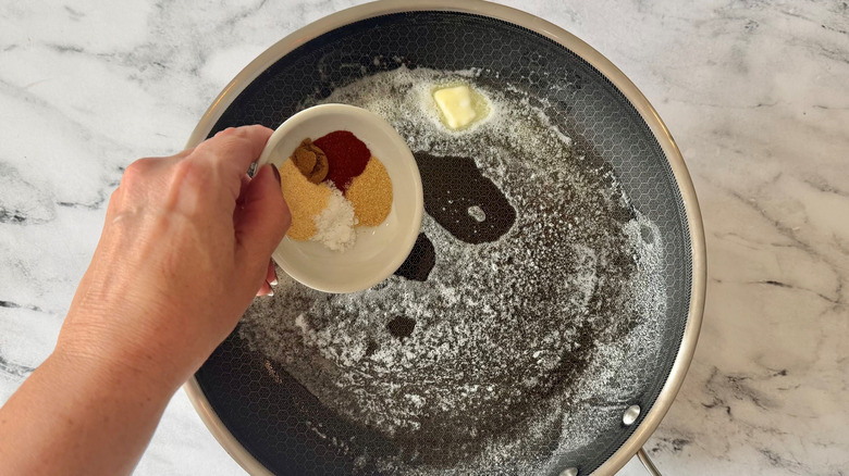 Hand adding spices to pan with melted butter