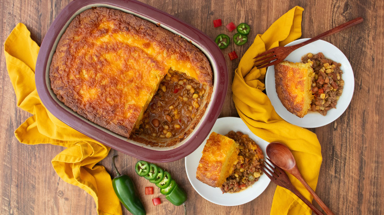 Cowboy cornbread casserole in dish next to servings on plates
