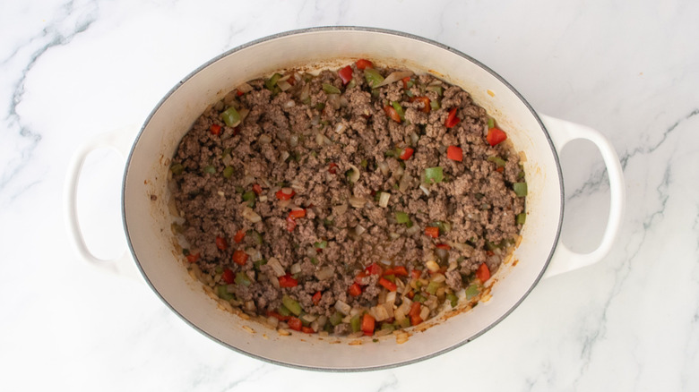 Ground beef and diced peppers in Dutch oven