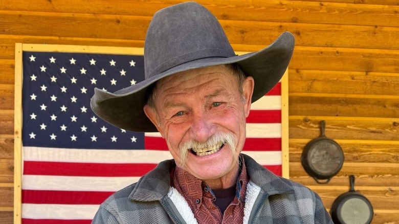 Kent Rollins smiling in front of U.S. flag backdrop