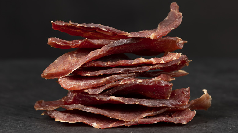 Stack of sliced beef jerky on gray surface.