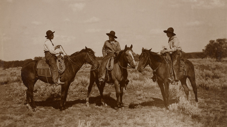 Historical photo of three cowboys on horseback.