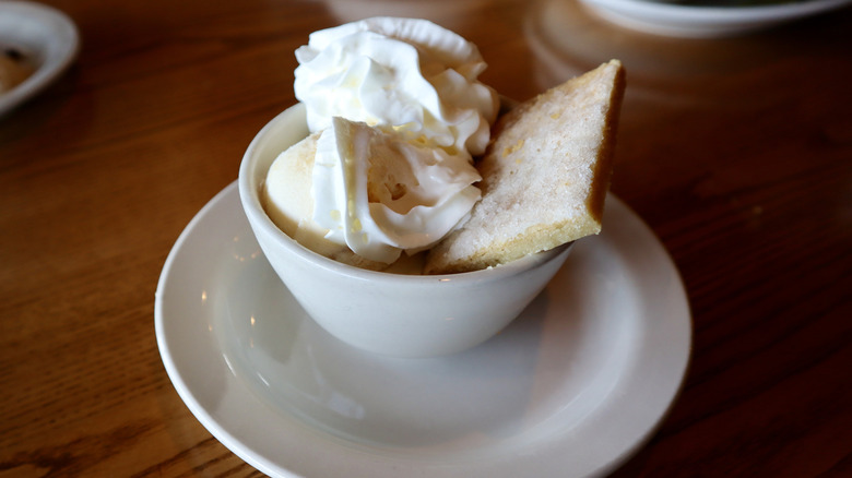 white cup with ice cream whipped cream and pastry