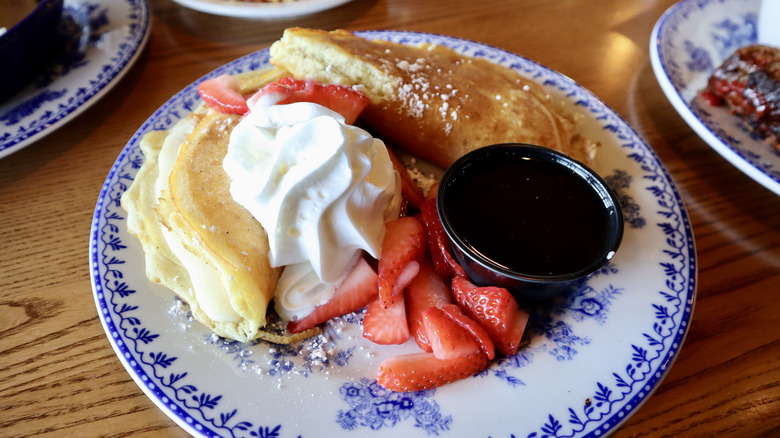 pancakes with whipped cream and strawberries on plate