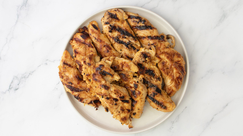Chicken tenderloins stacked onto plate