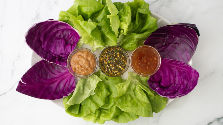 Lettuce leaves, cabbage, and sauces on serving platter