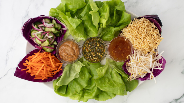 Lettuce platter with various vegetables, noodles, and sauces