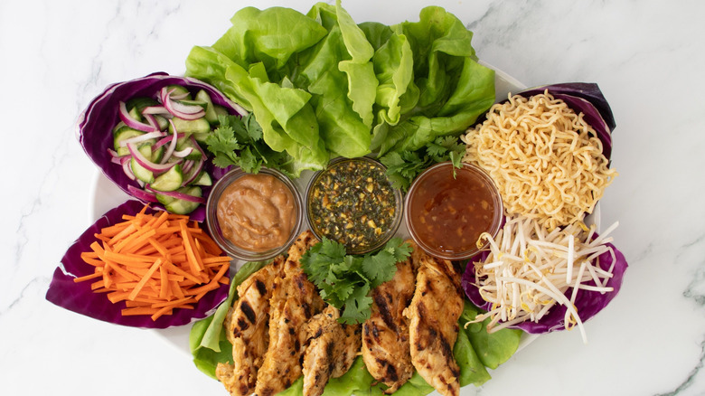 Thai lettuce platter with chicken, noodles, various vegetables, and sauces