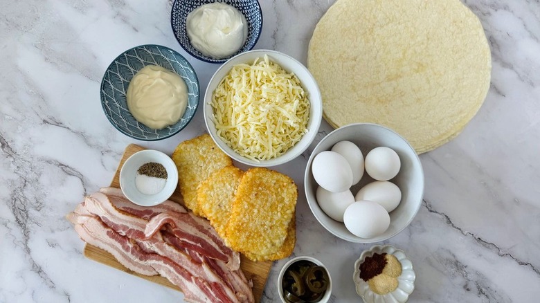 tortillas, eggs, bacon, cheese, hash browns, and other Crunchwrap ingredients laid out