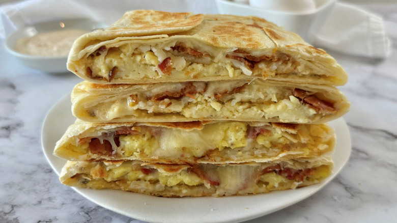 Stacked Crunchwraps showing eggs and bacon in flour tortillas