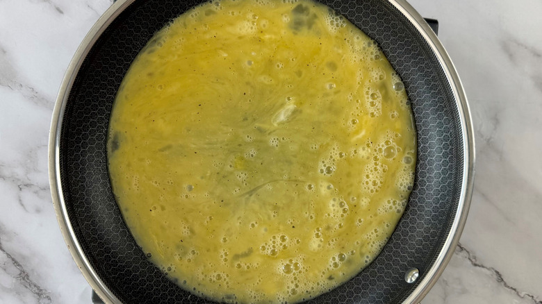 aerial view of raw beaten eggs in a frying pan