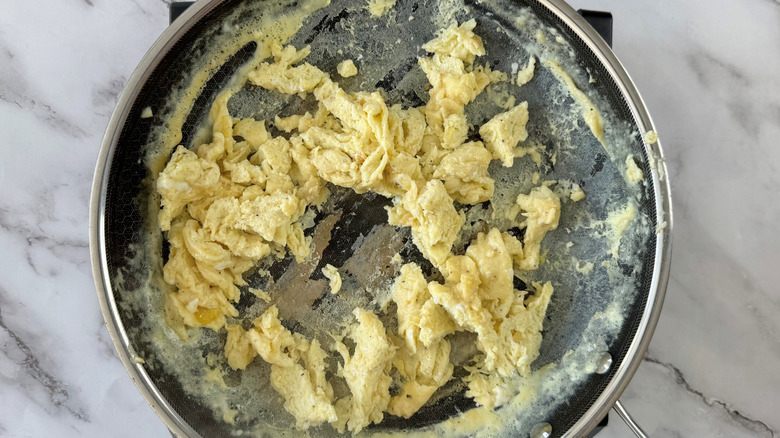 scrambled eggs in a frying pan with some egg sticking to the pan