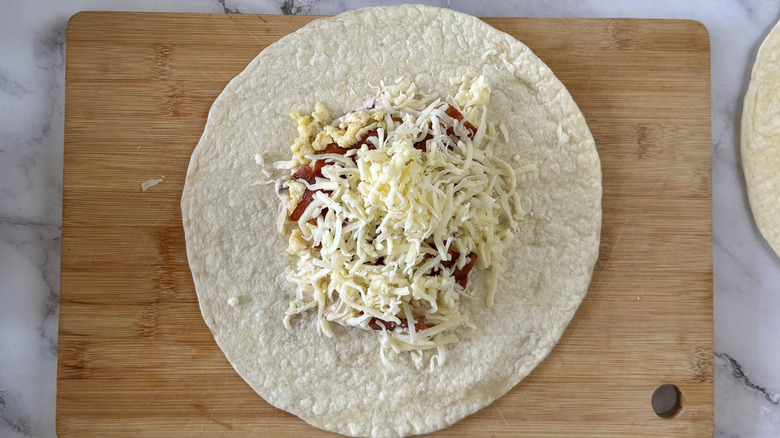 flour tortilla with shredded cheese on a cutting board