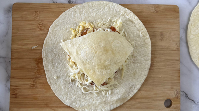 a piece of flour tortilla on a whole flour tortilla with toppings in between
