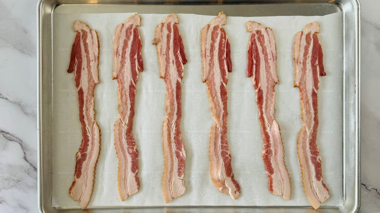 bacon strips spaced out in a lined baking pan