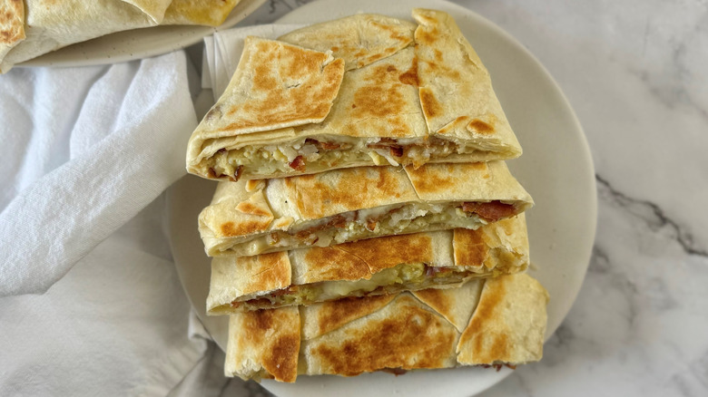 Copycat Crunchwraps with eggs and bacon in flour tortillas arranged on a plate