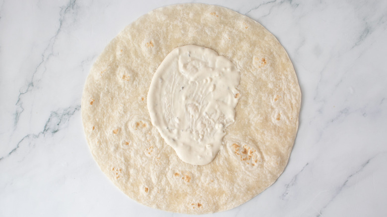 one flour tortilla smeared with salad dressing