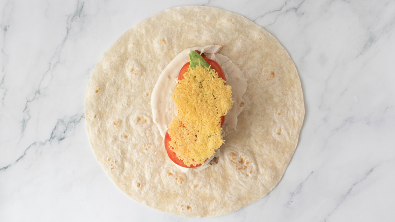 flour tortilla with salad dressing, vegetables, and baked cheese
