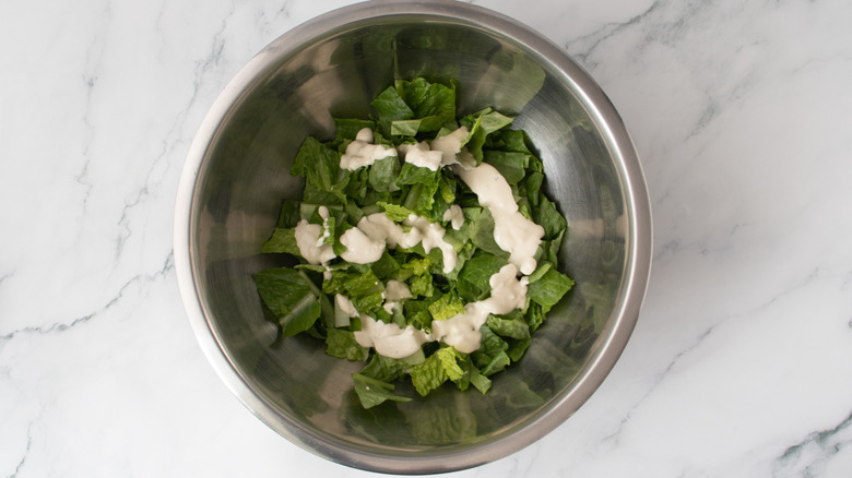 lettuce and dressing in a metal bowl