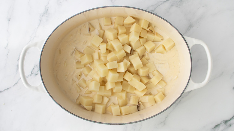 chopped potatoes and white liquid in a white pan
