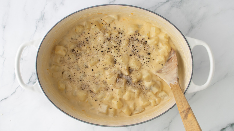 chopped potatoes in orangish liquid with black pepper