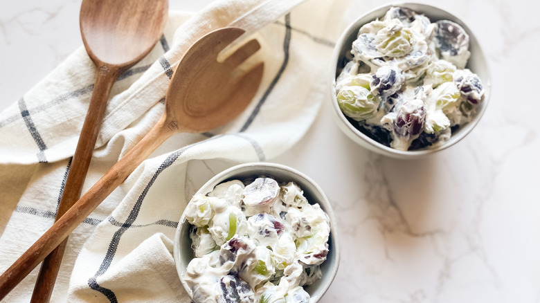 Creamy Grape Salad in bowls with wooden serving utensils