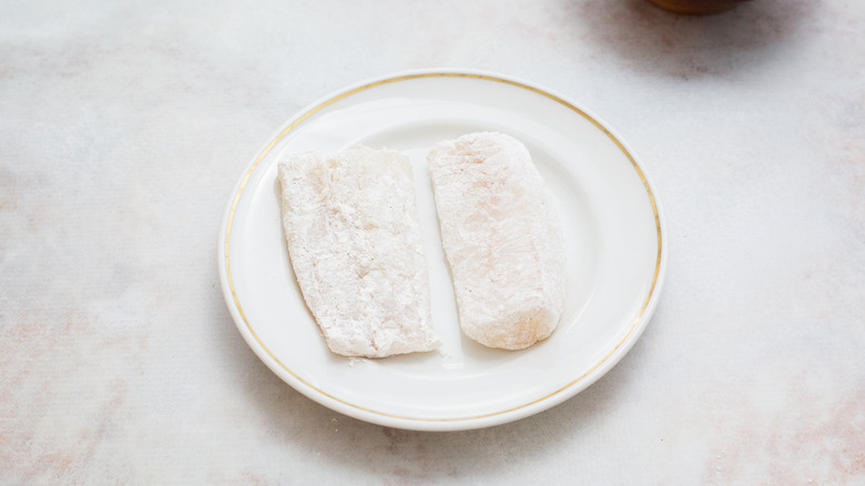 floured cod on white plate