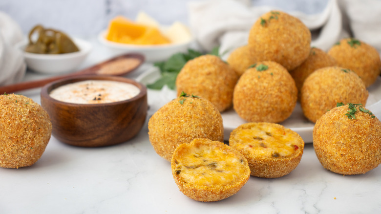 fried cheese balls on a white plate and a kitchen counter