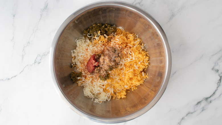 shredded cheese and chopped peppers in a metal bowl