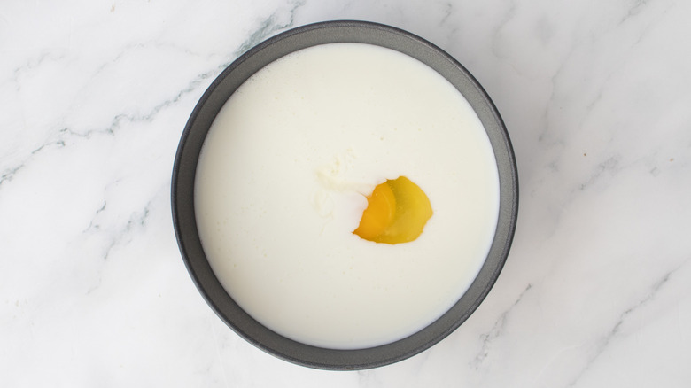 raw egg and milk in a metal bowl