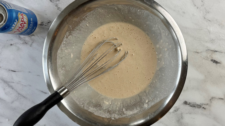 batter in a metal bowl next to a can of club soda