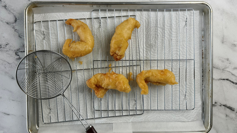 four battered chicken strips on a wire rack