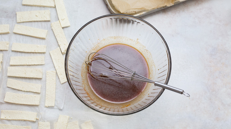 marinade in bowl on table next to tofu strips