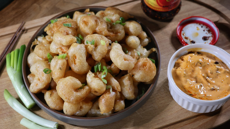 plate of tempura popcorn shrimp next to ramekin of orange dipping sauce