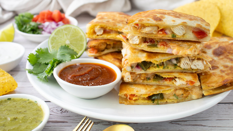 chicken quesadillas on a white plate with sauce in small bowls