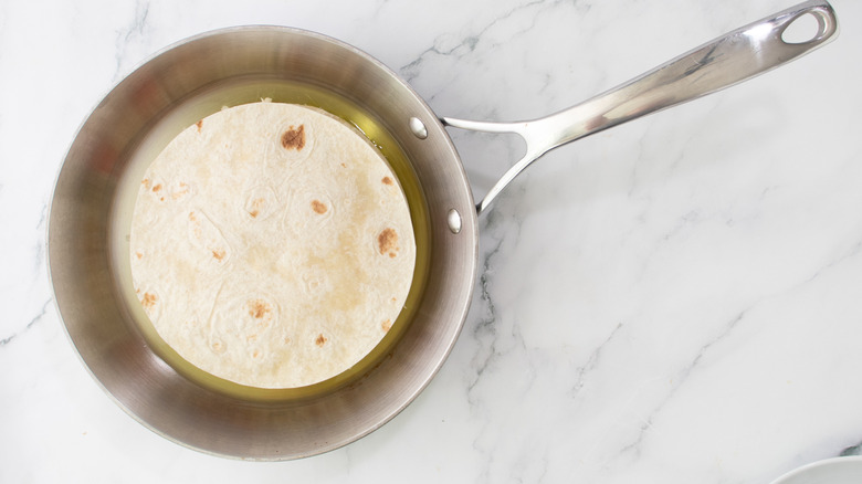 whole quesadilla sitting in oil in silver-colored frying pan