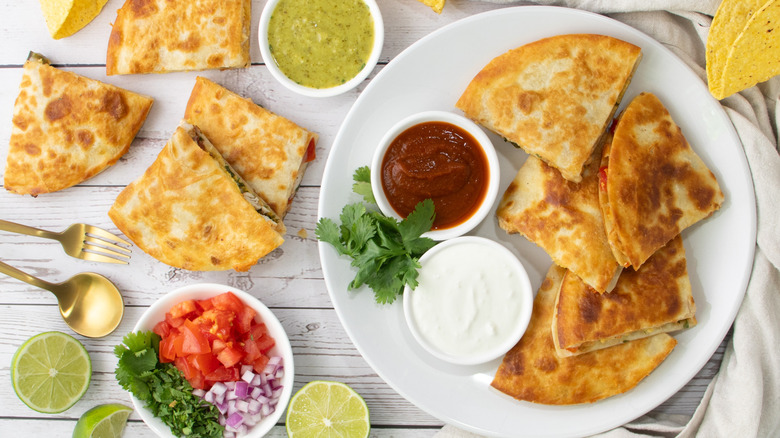 aerial view of sliced chicken quesadillas on a white plate and on wooden surface
