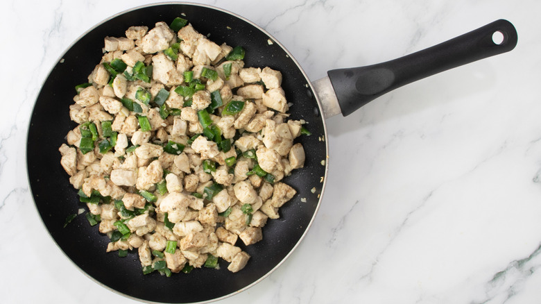 cooked chicken and peppers in a black frying pan