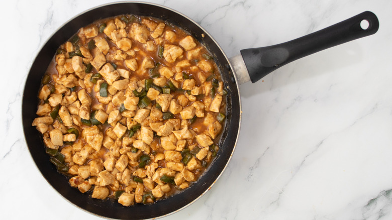 cooked chicken with barbecue sauce in a pan on a marble surface