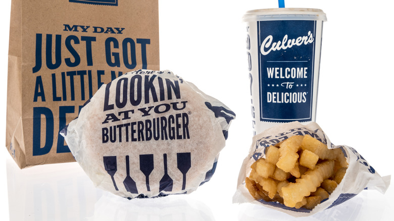 Culver's paper bag, paper-wrapped burger, soda cup with lid & straw, and paper bag of french fries