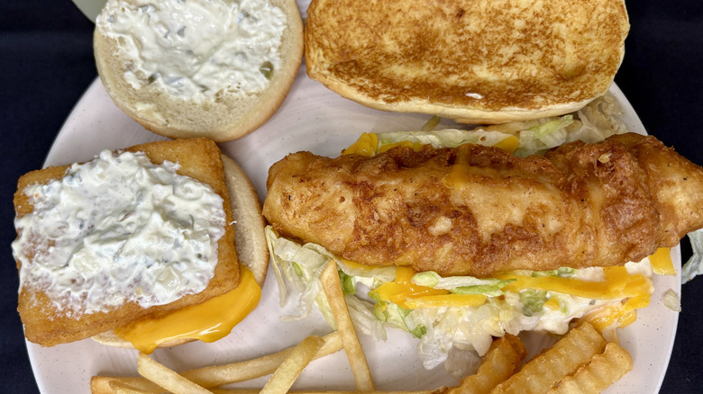 Top view of two fish sandwiches with the top buns removed on a white plate