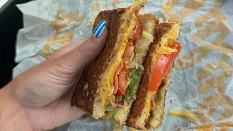 Hand holding a DIY BLT with cheese from Culver's