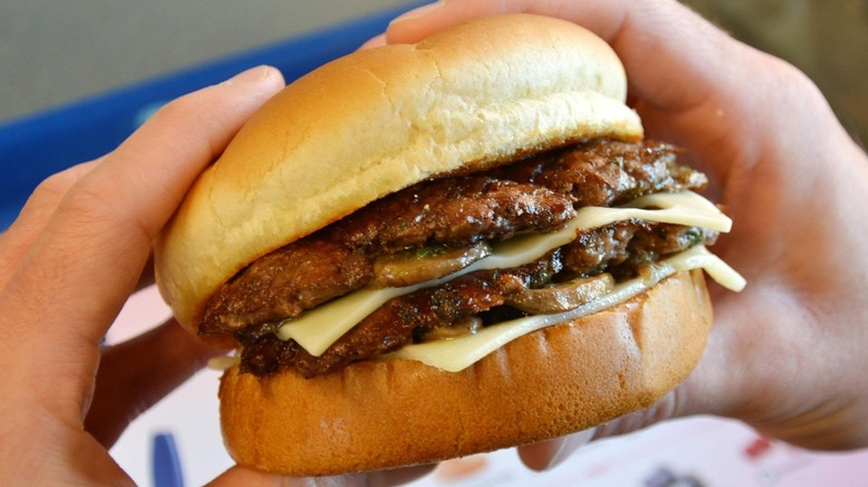 Hands holding Culver's Mushroom Swiss burger double